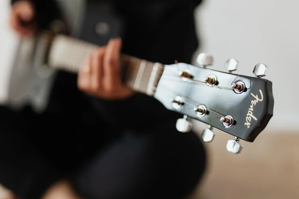 Primo piano di dita che regolano le chiavi di una chitarra