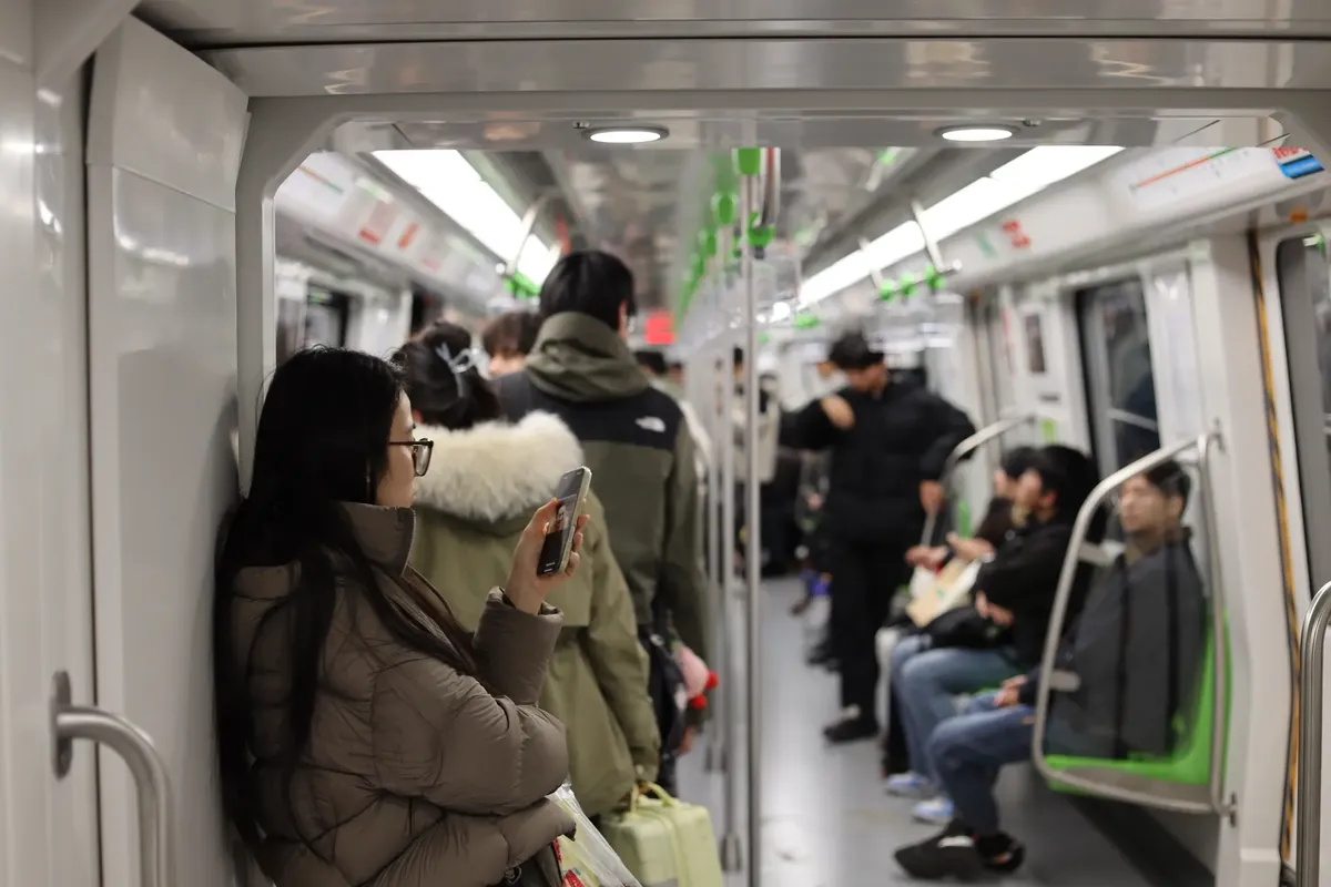 Commuters using mobile phones on a subway train in Nanjing, China, during winter.
