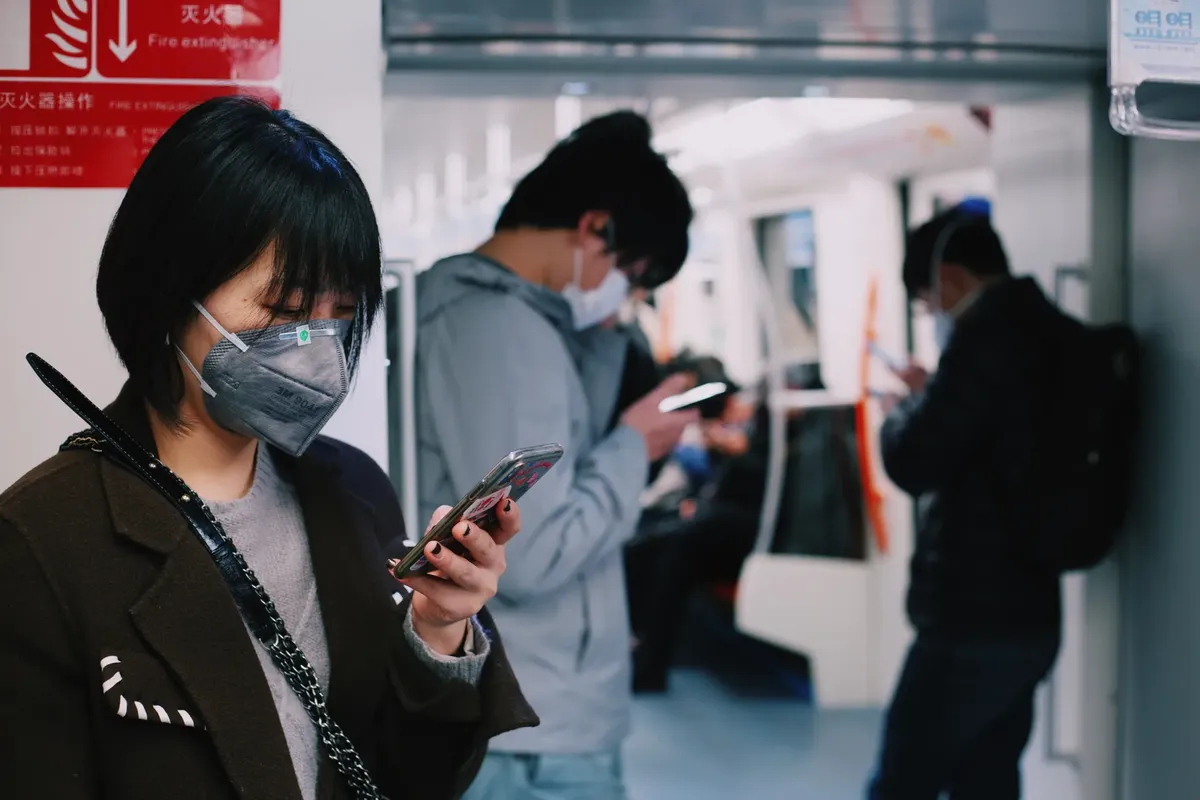 Adults wearing masks and using mobile phones on Shanghai subway amid COVID pandemic.