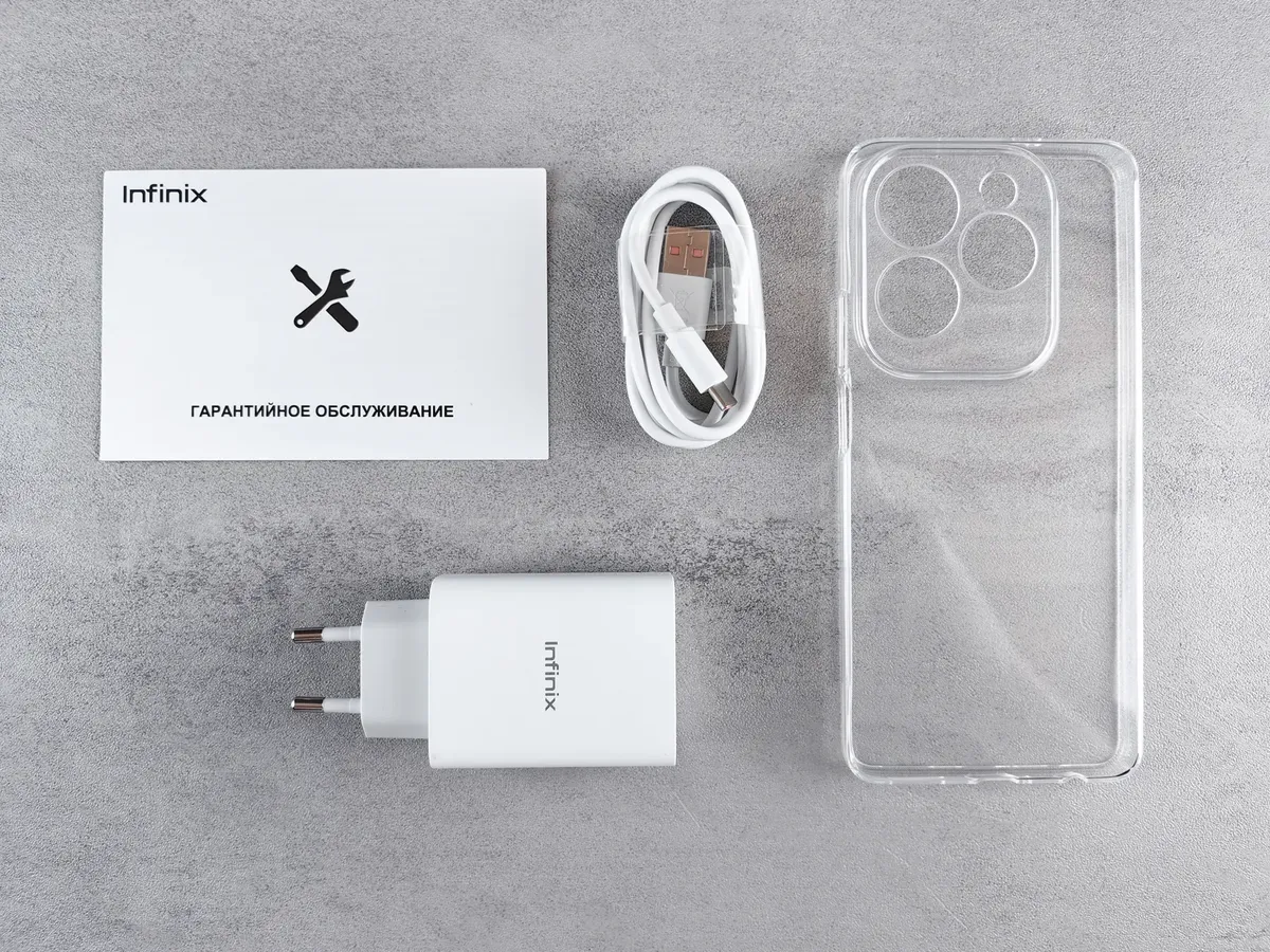 Flat lay of Infinix smartphone accessories with charger, cable, case, and warranty card.