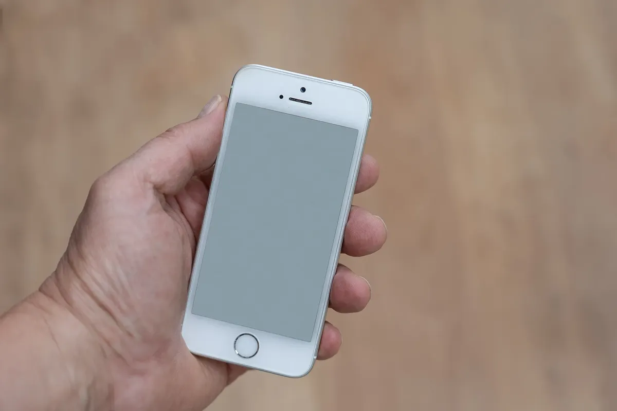 Close-up of a hand holding a smartphone with a blank screen, perfect for app mockups.
